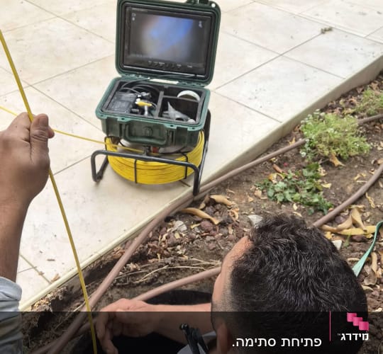 אינסטלטור מפעיל מצלמת דחיפה לבדיקת צנרת ביוב בחצר